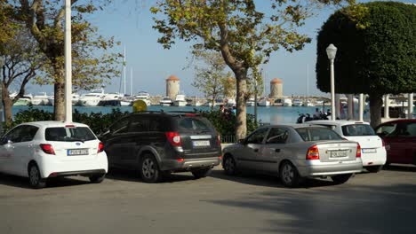 Cars-parking-by-the-harbour,-boats,-yachts-and-windmills-in-background