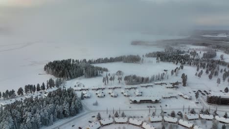 Aerial-view-around-clouds,-overlooking-the-Holiday-club-Katinkulta-resort-in-Vuokatti,-Finland---high,-circling,-drone-shot