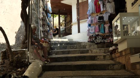 Anciana-Sentada-En-Las-Escaleras-Junto-A-Una-Tienda-De-Souvenirs-En-Lindos