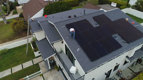 Blick-Von-Oben-Auf-Einen-Mann,-Der-Sonnenkollektoren-Auf-Dem-Dach-Eines-Vorstadthauses-Installiert