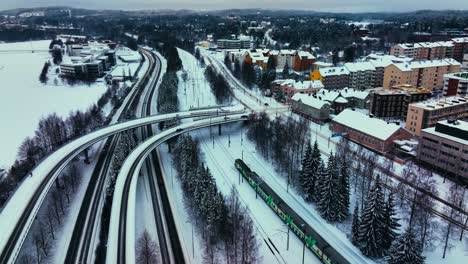 Aerial-view-around-a-train-leaving-Jyvaskyla-city,-winter-evening-in-Finland---circling,-drone-shot