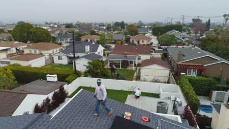 Aerial-view-over-technicians-doing-maintenance-of-solar-energy-generators-on-top-of-a-house---reverse,-drone-shot