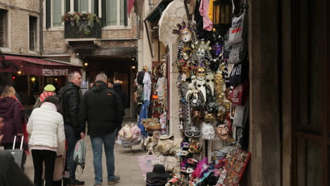Men-Looking-At-Venetian-Mask-Suivenir-Shop-At-Carnival-Time,-Narrow-Street,-Venice