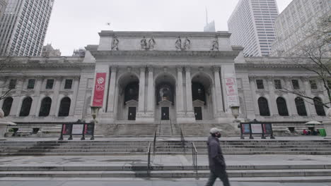 Wide-shot-of-New-York-Public-Library-with-men-wearing-face-mask-walking