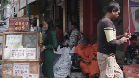 Junge-Mönche-Warten-Und-Sitzen-Auf-Einem-Straßenmarkt-Im-Freien-In-Kambodscha