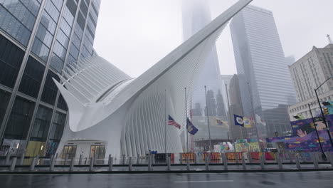 Empty-sidewalk-front-of-the-Oculus-on-a-rainy-day-with-American-flag-flying-in-slow-motion