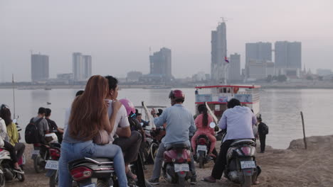 Cambodian-on-motorcycle-waiting-for-Ferry-across-Tse-Long-River-in-Phnom-Penh-Diamond-City-in-background