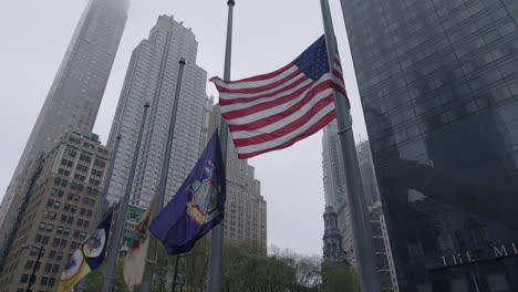 Amerikanische-Flagge-Mit-New-Yorker-Flagge,-Die-An-Einem-Nebligen-Tag-In-Zeitlupe-In-Der-Innenstadt-Von-Manhattan-Weht