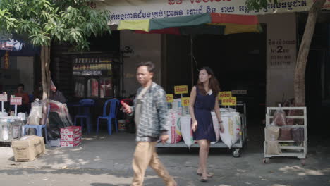 Frauen-Gehen-Vor-Einem-Freiluftmarkt,-Auf-Dem-Reis-In-Großen-Mengen-Auf-Der-Straße-Von-Phnom-Penh-Verkauft-Wird