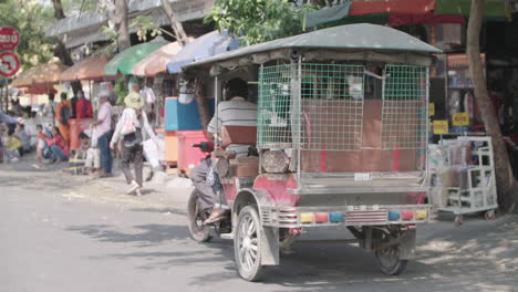 Tuk-Tuk-Camboyano-Despegando-Frente-A-Un-Mercado-Al-Aire-Libre-En-Phnom-Penh
