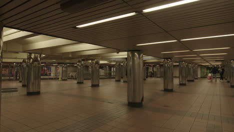 Empty-subway-transit-hall-with-homeless-and-people-wearing-face-mask