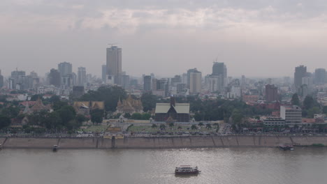 Zoom-out-from-Ferry-Boat-on-Tonle-sap-River-to-wide-shot-of-Phnom-Penh-Skyline