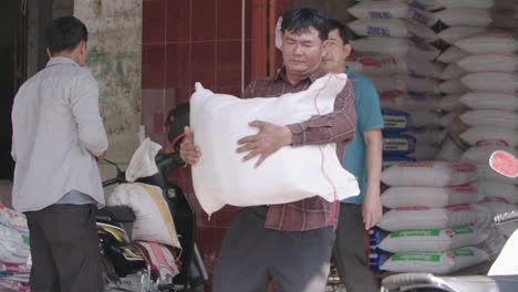 Buyer-pick-up-a-heavy-bag-of-rice-from-a-merchant-on-an-outdoor-rice-market-in-Cambodia