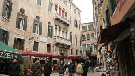 Narrow-Crowded-Street-With-Pizzeria-And-Gift-Shop-In-Venice,-Winter-Carnival-Time,-Tilt