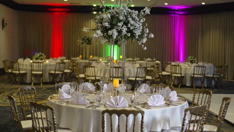 Round-table-decorated-for-wedding,-tall-centerpiece-with-Gypsophila-paniculate-flowers,-white-roses-and-green-foliage