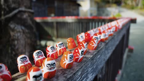 Daruma-good-luck-dolls-on-fence-in-line-at-Katsuo-ji-Temple-in-Minoh-Osaka