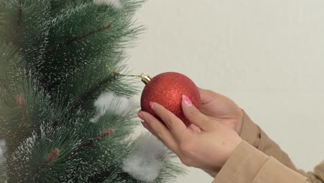 Die-Hand-Eines-Mädchens-Hängt-Eine-Rote-Christbaumkugel-Aus-Nächster-Nähe-An-Den-Weihnachtsbaum