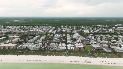 Straight-Back-motion-wide-view-of-Rosemary-Beach-Town,-Western-Green-with-beach-front-with-asky-horizon-on-the-back