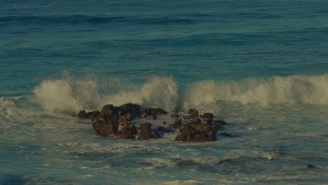 the-camera-follows-the-white-capped-crest-of-the-aqua-waters-of-the-Pacific-ocean-as-the-crash-into-shore-on-the-volcanic-beach-in-hawaii-on-the-island-of-Oahu