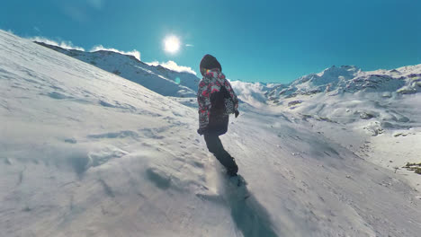 Rear-view-of-professional-snowboarder-riding-down-the-mountain-slope-at-sunny-winter-day-in-French-Alps