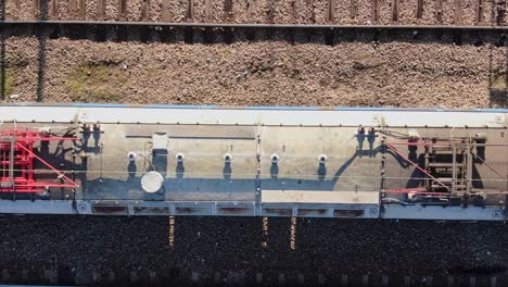 Locomotive-and-tanker-wagon-transporting-gasoline-on-railroad,-aerial-top-down