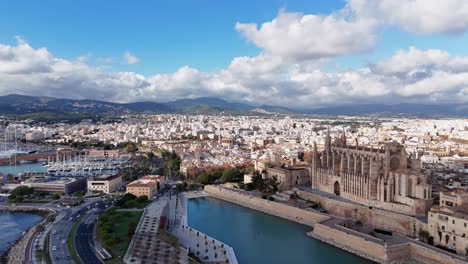 Aerial-establishing-shot-showing-traffic-on-coastal-road-and-famous-Cathedral-de-Mallorca-in-Palma-City