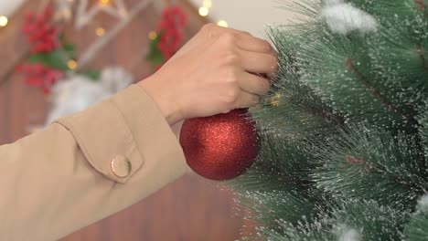 Mädchenhand-Hängt-Rote-Dekorationskugel-Am-Adventsritual-Des-Weihnachtsbaums