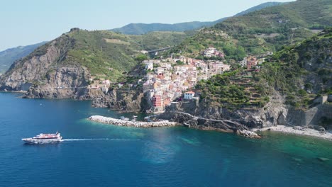 Cinque-Terre-Boat-Tour-and-Riomaggiore-Village-in-Vernazza,-La-Spezia,-Liguria,-Italy---Aerial-4k-Circling