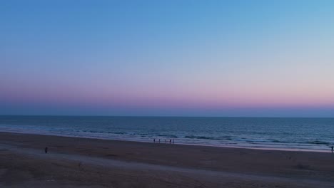 Sonnenuntergangsfarben-Am-Horizont-An-Einem-Ruhigen-Strand-Mit-Wenigen-Besuchern