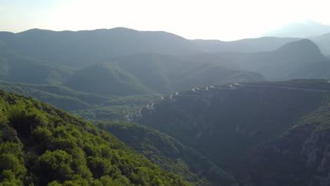 A-distant-aerial-view-captures-the-serpentine-narrow-road-leading-to-Vikos-Gorge-in-Northern-Greece,-a-route-filled-with-twists-and-turns-sharply-winding-up-the-mountain-in-the-Zagori-region