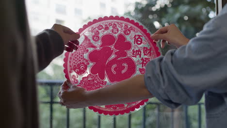 Chinesisches-Neujahrspaar-Klebt-Fensterglas-Auf,-Ein-Traditionelles-Dekoratives-Element-Für-Die-Traditionelle-Partyfeier