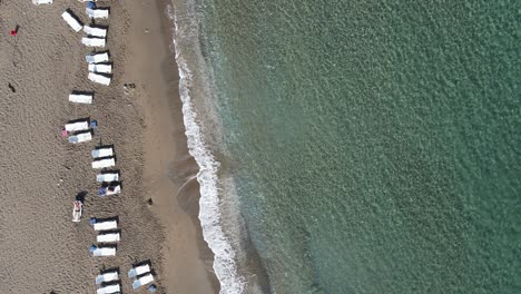Drone-view-of-people-lying-on-sun-loungers-on-the-beach-on-a-sunny-day