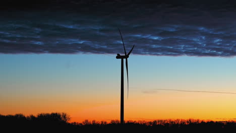 Silhouette-wind-power-generator-with-dramatic,-vibrant-sunset-sky-background