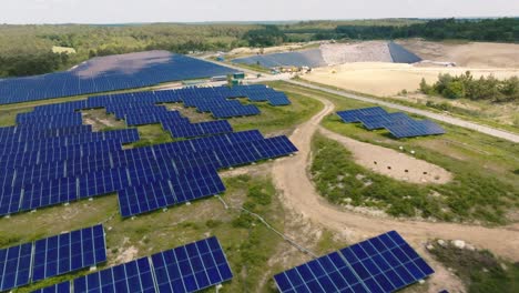 Lateral-and-forward-motion-in-solar-panels-seen-from-a-drone-with-a-landfill-in-the-background