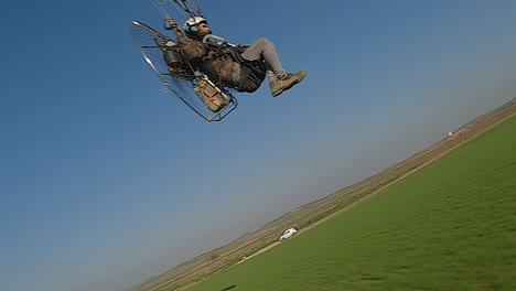 Close-proximity-aerial-zooms-past-motor-paraglider-in-countryside