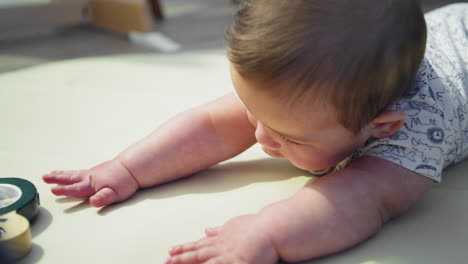 Baby-boy-smiling-on-the-ground-while-on-his-stomach-learning-how-to-crawl