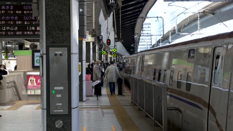 Commuter-Walking-Along-Station-Platform-Beside-Bullet-Train-At-Station