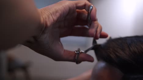 Scissors-being-used-on-front-side-of-head-to-trim-hair,-filmed-from-rear-side-of-scissors-in-closeup-slow-motion-style