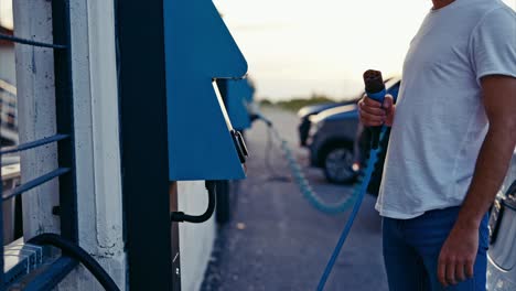 Unrecognizable-young-man-charging-his-electric-car-at-public-charging-station