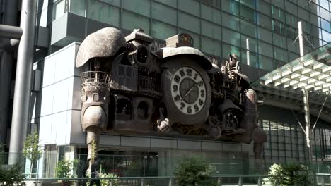 View-Of-The-Ni-Tele-large-clock-and-sculpture-,-a-creation-by-Hayao-Miyazaki,-has-been-installed-on-the-exterior-of-the-second-floor-of-Nittele-Tower-in-Minato-Ward,-Japan