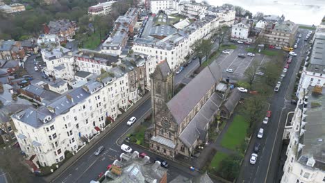 Aerial-parallax-shot-of-St-Martin-Church-surrounded-by-tall-white-vintage-buildings-during-daytime-in-Scarborough