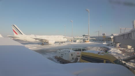 POV-Of-A-Passenger-Looking-Through-The-Window-Of-Airplane-Partly-Covered-With-Snow-At-Munich-Airport-In-Germany