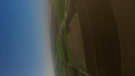 Vertical-format:-Aerial-view-of-motor-paraglider-flying-over-fields