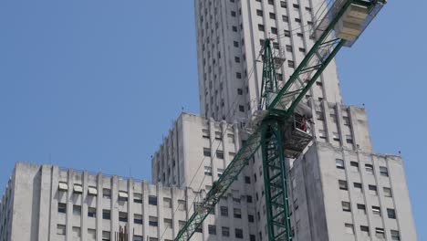 Dynamic-Aerial-Footage-Capturing-a-Crane-in-Motion,-Busily-Constructing-a-Building-in-the-Heart-of-Buenos-Aires,-Showcasing-the-Urban-Growth-and-Development-in-the-Bustling-City-Center-during-daytime