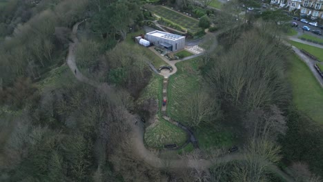 Aerial-backward-shot-of-a-house-situated-between-dense-trees-and-a-small-path-in-Scarborough-bay,-England