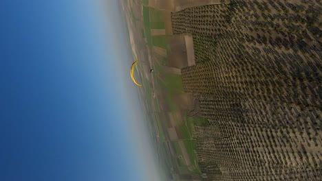 Vertical-format:-Aerial-catches-paramotor-glider-in-blue-sky-of-Spain