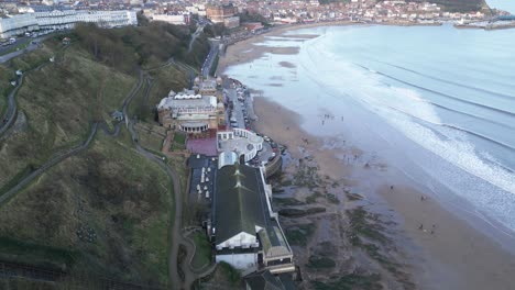Side-view-aerial-shot-of-Scarborough-Spa-in-front-of-beach-with-small-tides-during-daytime-with-beautiful-cityscape-in-North-Yorkshire,-England