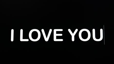 Close-up-of-I-LOVE-YOU-being-typed-into-computer-monitor-screen-with-blinking-cursor-on-black-background-copy-space