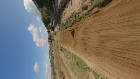 Vertical-format:-Fast-FPV-spins-around-motocross-bike-racer-on-dirt