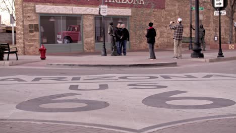 Arizona-Route-66-painting-on-street-in-Winslow,-Arizona-to-tilt-up-to-people-in-slow-motion